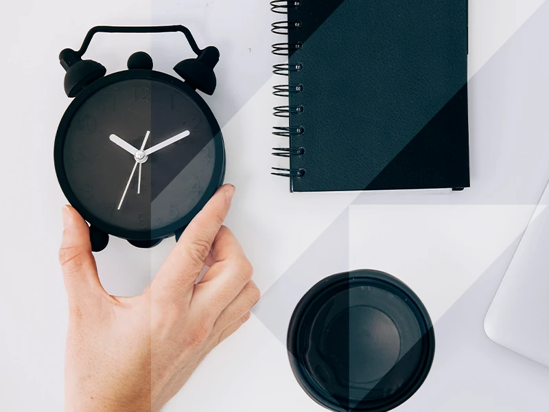 mano sosteniendo un reloj spbre escritorio